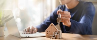 Businessman choosing mini wood house model. Planning to buy property. Choose what's the best. A symbol for construction, ecology, loan concepts.